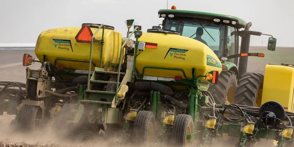 Tractor with precision planting equipment in a dusty field.