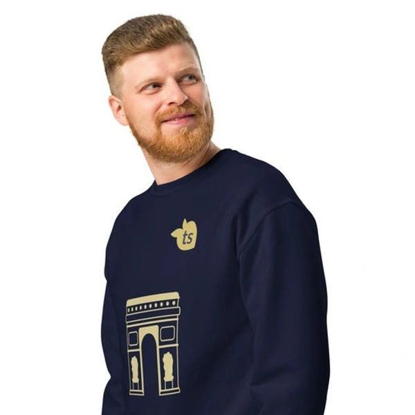 Man wearing a navy sweatshirt with a gold design of an arch and apple logo.