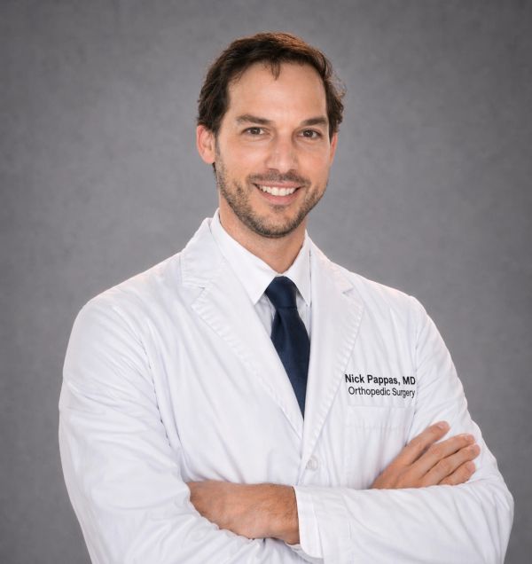 Smiling male doctor in white coat with arms crossed.