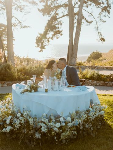 Couple sitting at sweetheart table on bluff at Seascape Beach Resort Aptos, CA in floral meadow 