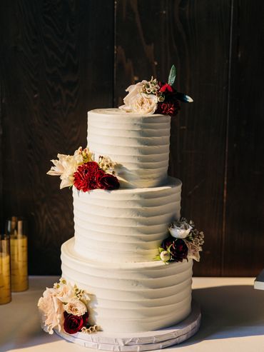 Cake decorated with florals, burgundy, peach flowers on wedding cake, three tier cake with flowers