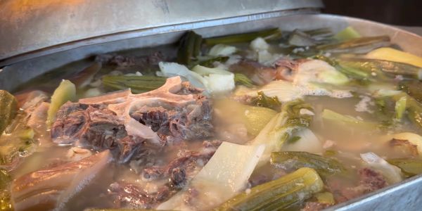 Close-up of meat and vegetables cooking in broth.