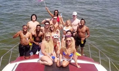 Group of people wearing swimsuits having fun on the bow of a private yacht rental on Lewisville Lake