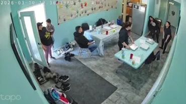 People gathered in a room with tables and chairs, engaging in conversation.