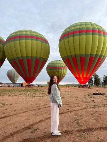 Woman standing near colorful hot air balloons on the ground.