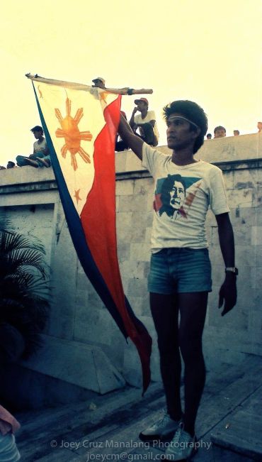 Man holding a Philippine flag, wearing a Bob Marley t-shirt and headband.