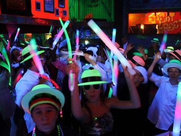 group of people in a dark neon room holding glow sticks in the air