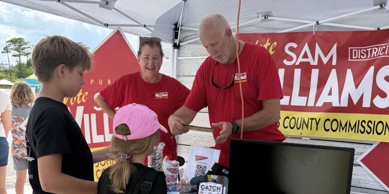 People at a campaign booth for Sam Williams County Commissioner.