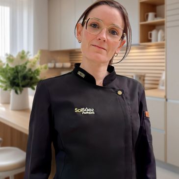 Professional chef in a modern kitchen wearing a black uniform.