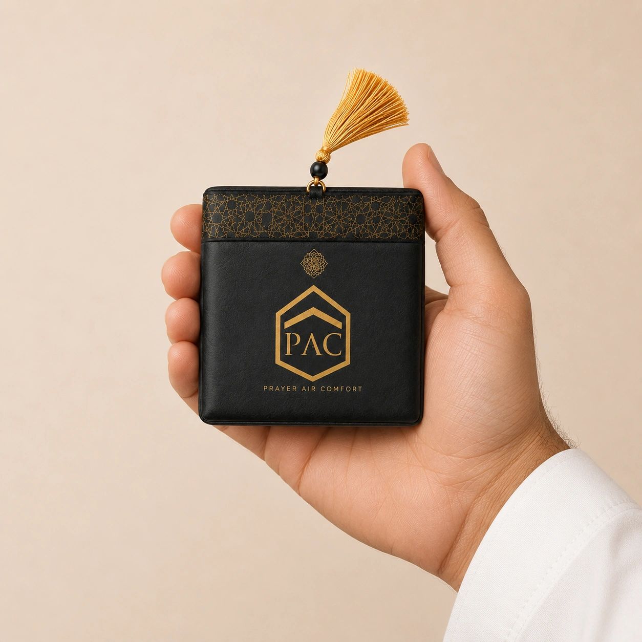 Hand holding a sleek black prayer accessory with a golden tassel.