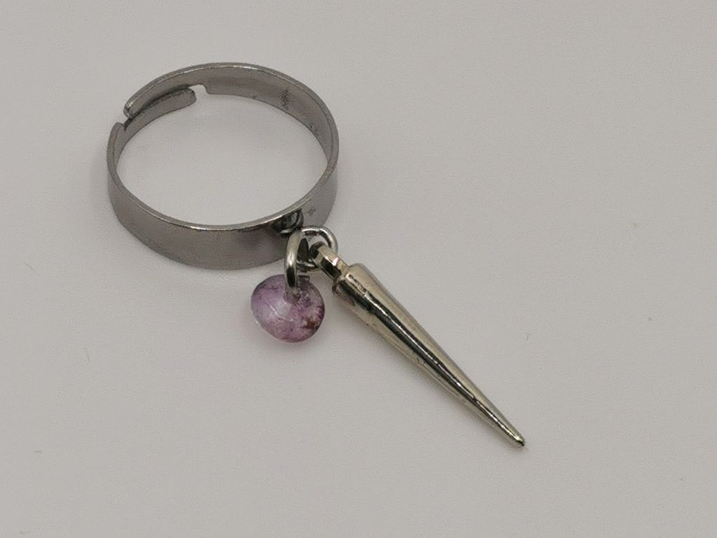 Silver ring with a pointed charm and a small purple bead.
