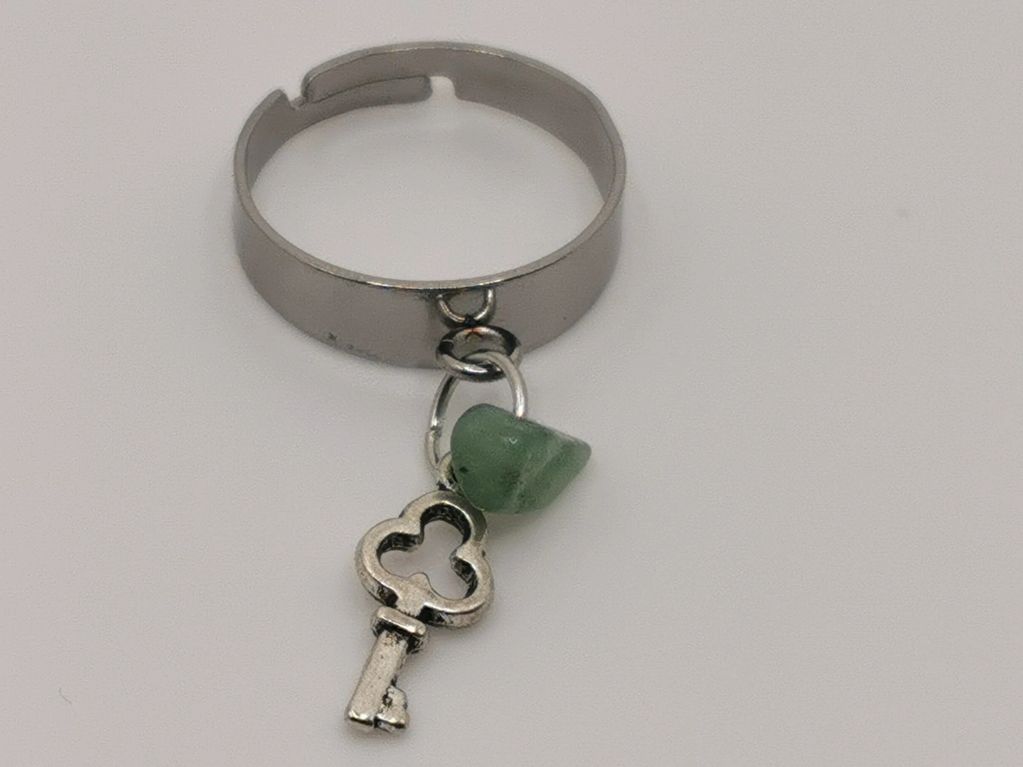 Silver ring with key and green stone charm.
