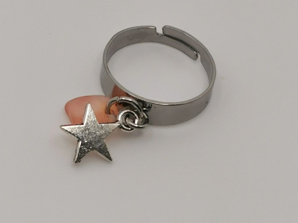 Silver ring with star charm and pink stone.