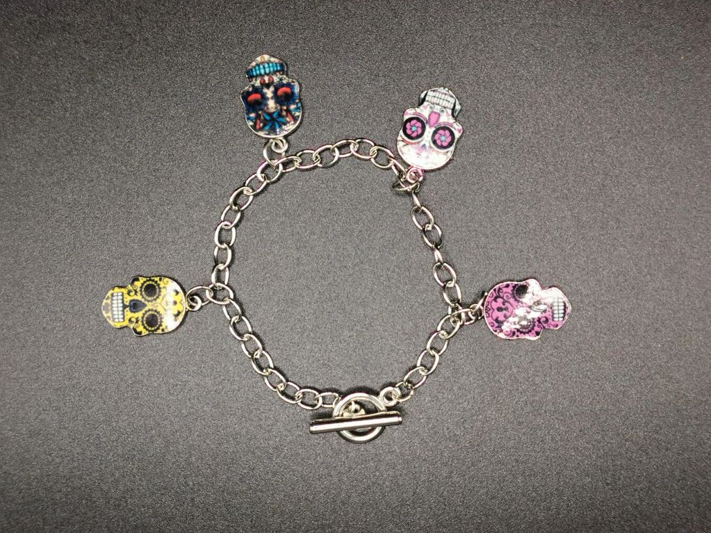 Bracelet with colorful skull charms on a black surface.