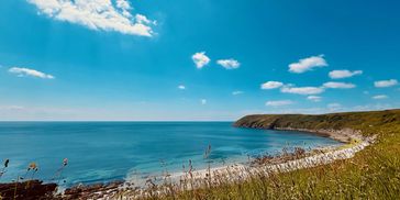 long crescent beach, with a beautiful azure sea, and bright blue sky over hear