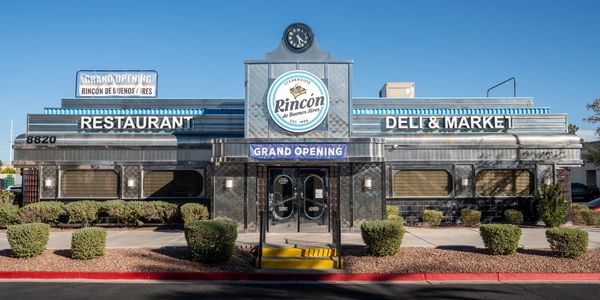 Exterior of Rincon de Buenos Aires restaurant and deli with grand opening sign.