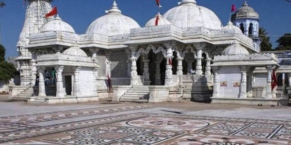 White marble temple with intricate carvings and tiled courtyard.