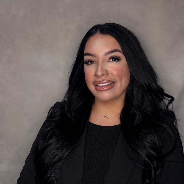 Smiling woman with long black hair in a black blazer.