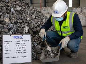Worker collecting silico manganese samples in a warehouse.