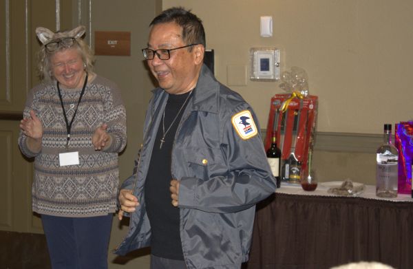 Two people smiling and enjoying a moment indoors, one wearing a postal service jacket.