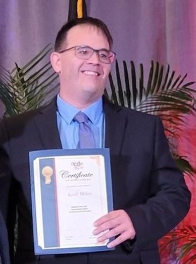 A man in a suit holding a certificate and smiling.