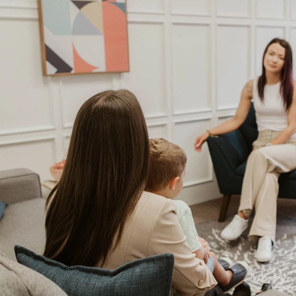 Woman consulting with mother and child in a cozy office.