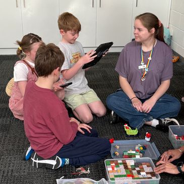 Children and a teacher engaging in an educational activity with tablets and board games.