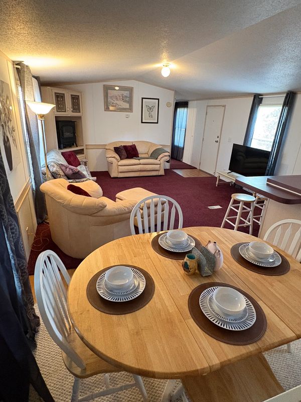 Cozy living and dining area with beige sofas and a wooden table set for four.