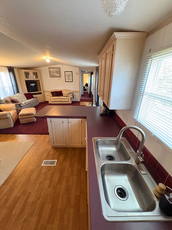 Cozy living room and kitchen area with wooden floors and burgundy accents.