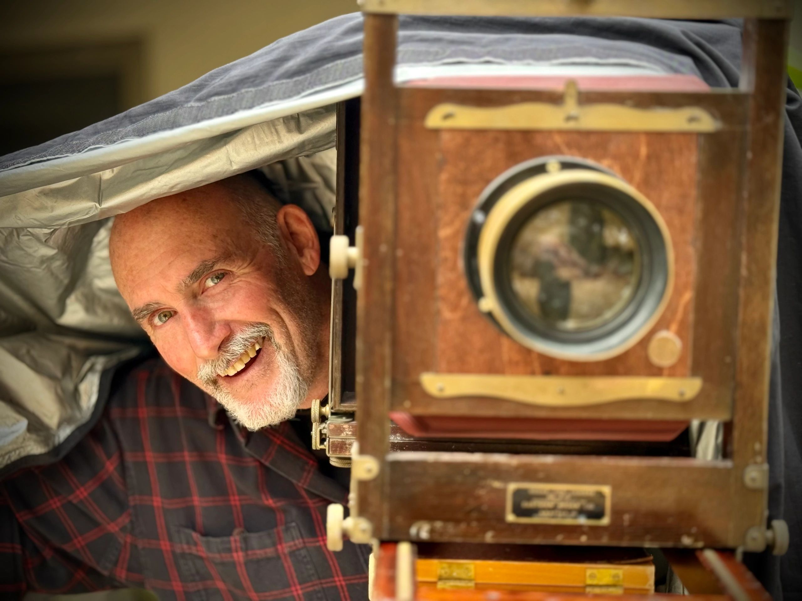 Man smiling behind an antique camera.
