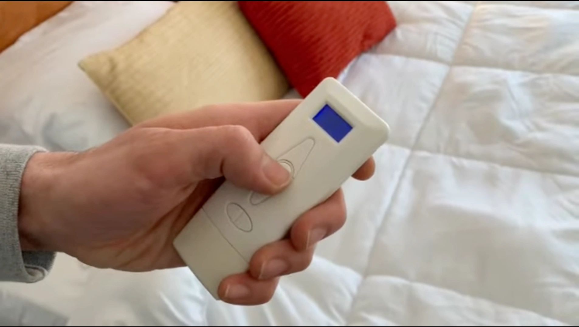 Hand holding a remote control with a blue screen.