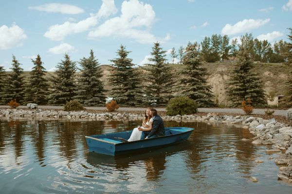 Couple enjoying a romantic boat ride on a tranquil lake surrounded by trees.
