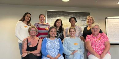 Group of nine women posing together indoors.
