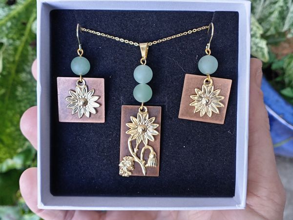 Hand holding a box with floral-themed gold and green adventurine jewellery set.