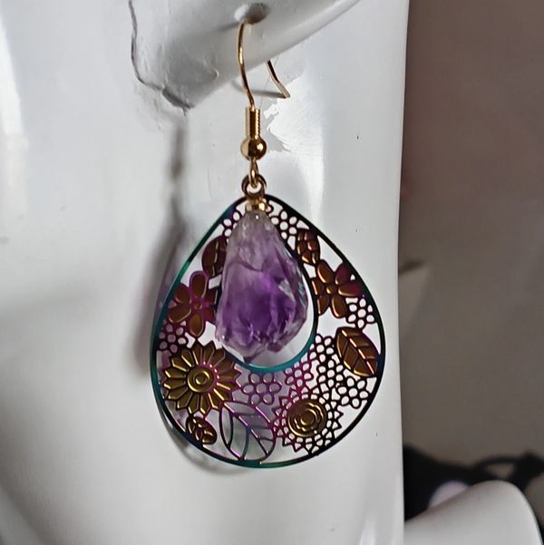 Intricate earring with amethyst stone on white mannequin.