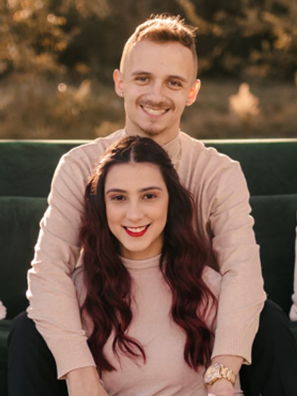 A smiling couple embracing outdoors with warm lighting.