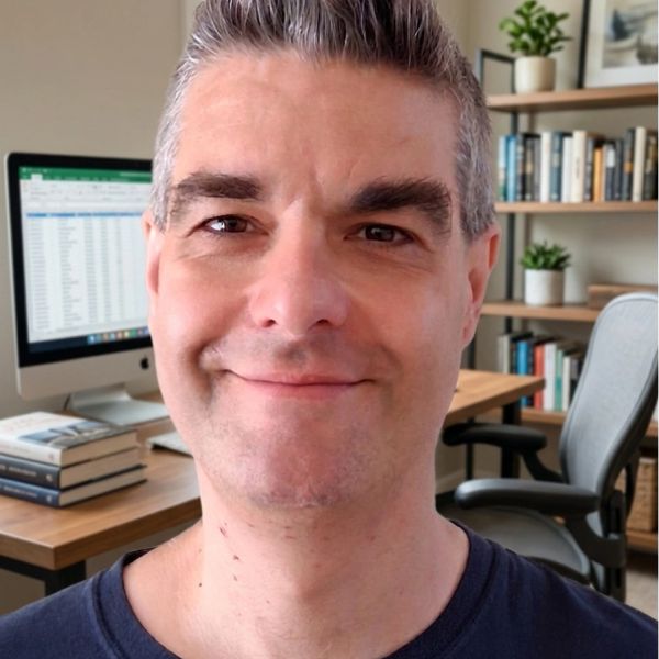 Man smiling in home office with computer and books.