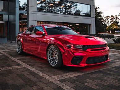 A Dodge Charger parked in front of a modern building, showcasing its sleek wrap design.