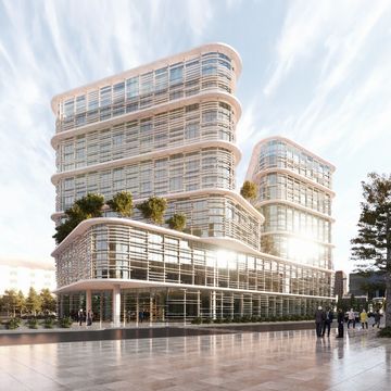 Modern glass building with greenery and people around in a spacious plaza.
