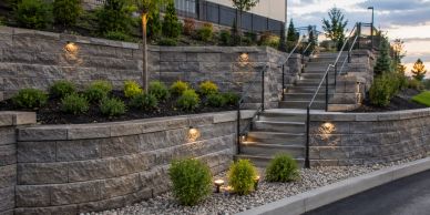 Stone retaining walls and stairs illuminated by lights.