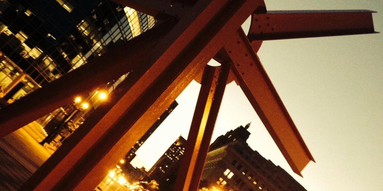 Cityscape at dusk with metal beams in foreground.