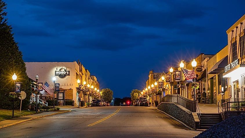 Quiet small-town street illuminated by streetlights at dusk.