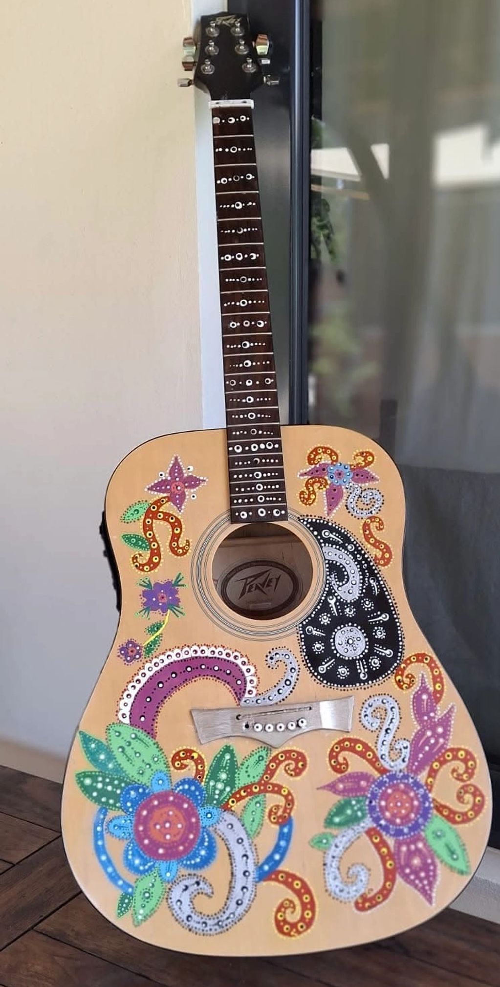 Acoustic guitar with colorful floral and paisley designs.