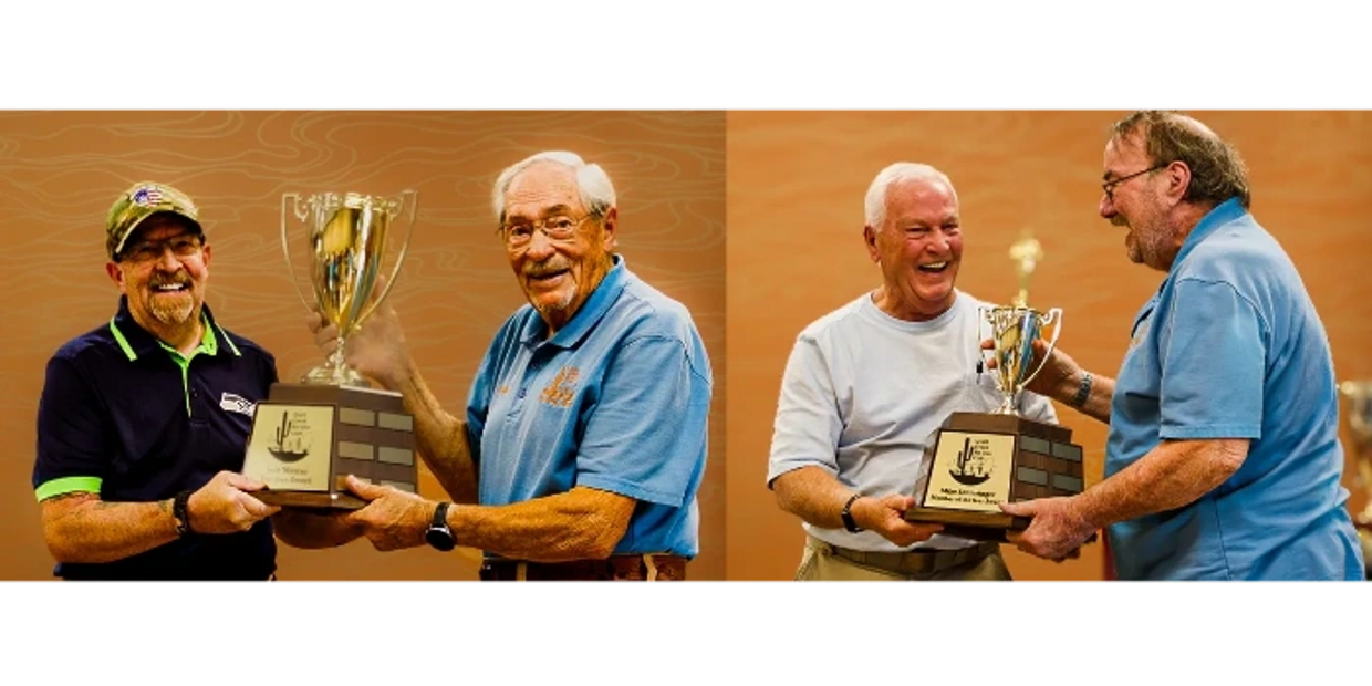 Two pairs of elderly men smiling while holding trophies together against an orange backdrop.