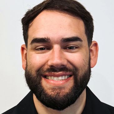 Smiling man with a beard and dark hair.