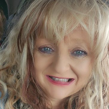 Smiling woman with curly blonde hair and blue eyes.