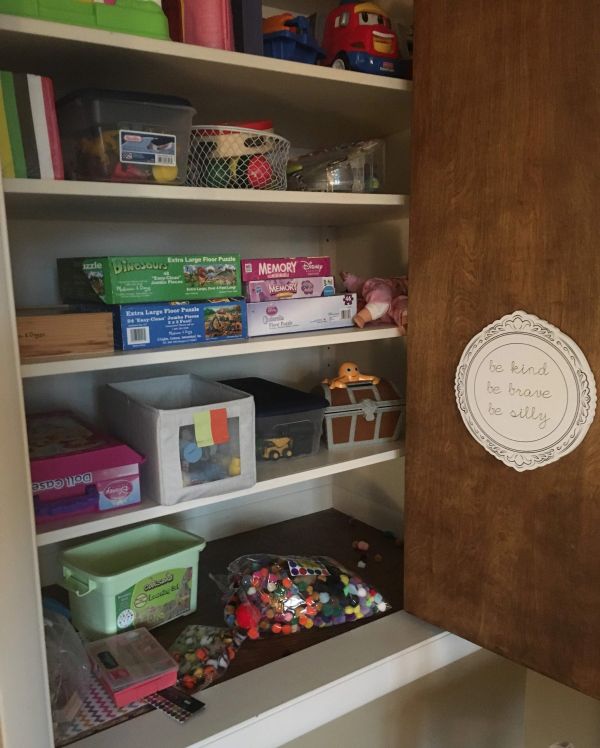 Organized shelves with puzzles, toys, and a positive message on the door.