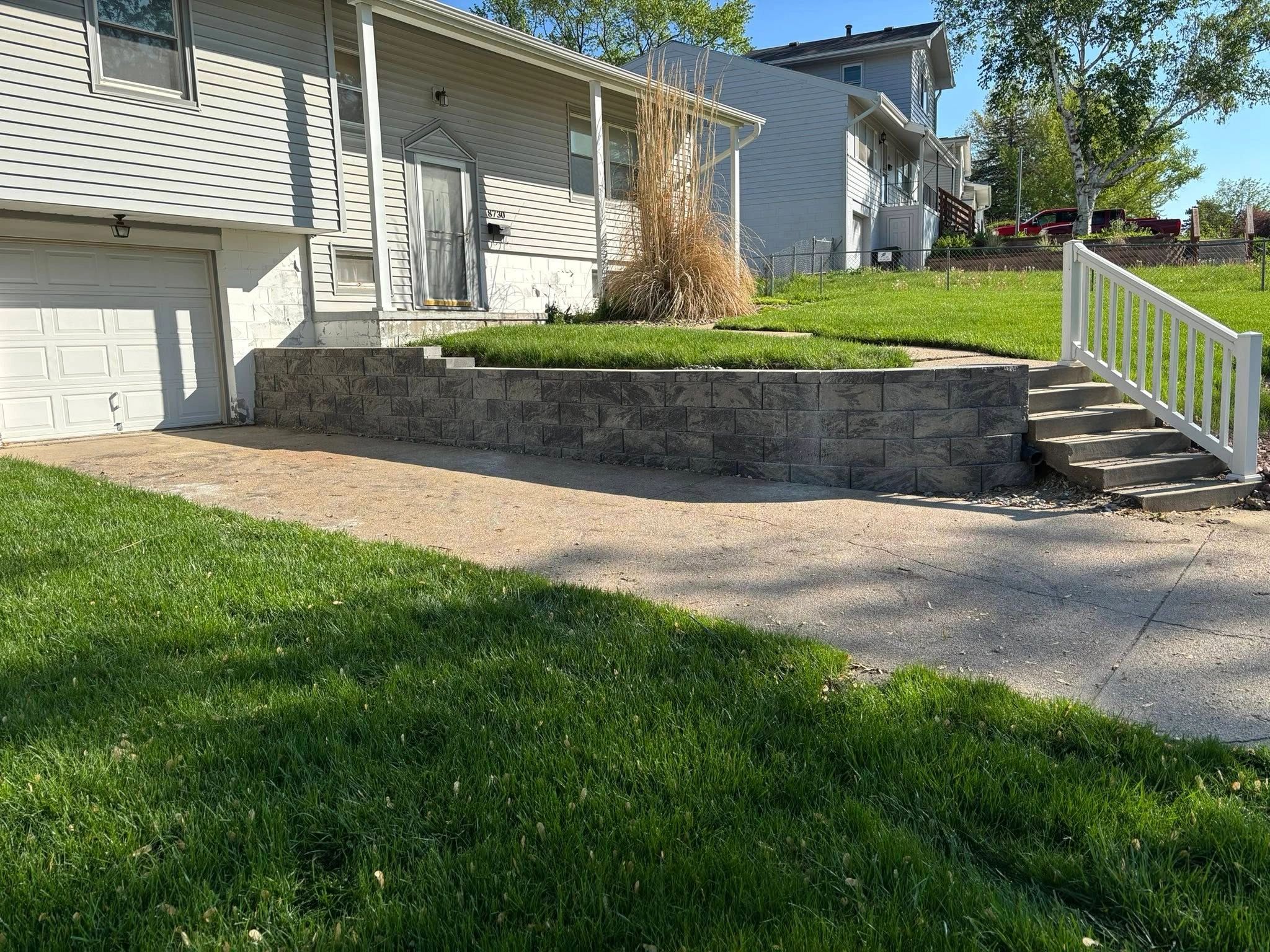 Well-maintained suburban front yard with retaining wall and stairs.