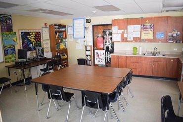 Elementary classroom with tables and chairs.