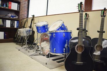 A music room with drums and acoustic guitars.